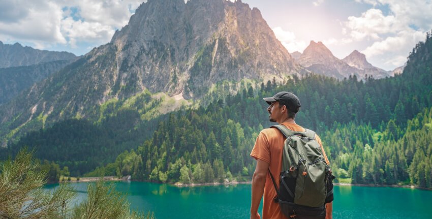 Traveller with a backpack above a mountain lake